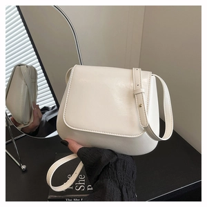 Detail of white glossy leather shoulder bag showing adjustable strap and metal buckle