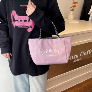 Minimalist light purple nylon tote bag with woven handles shown in a lifestyle setting