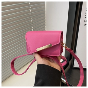 Détail du mini sac bandoulière rose fuchsia avec une barre décorative en métal doré