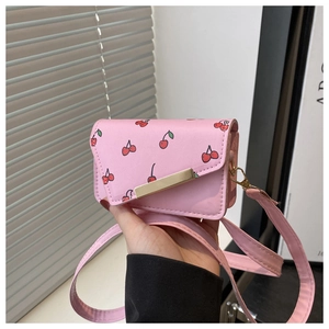 Détail d'un sac bandoulière rose à motif cerise avec garniture dorée en cuir PU