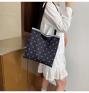 Detailed view of black floral canvas tote bag with white lace trim and straps