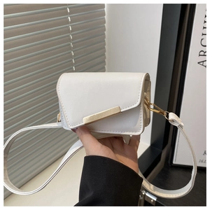 Gros plan d'un mini sac à rabat blanc avec un fermoir doré en métal tenu à la main