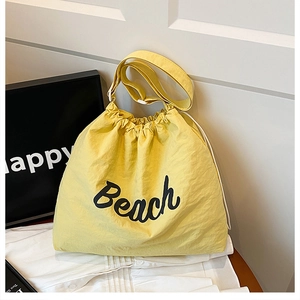 Yellow drawstring bucket bag with Beach lettering and wide adjustable shoulder strap