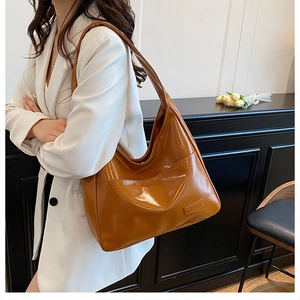 Detail view of large dark brown retro PU tote bag with functional side pocket on wood background