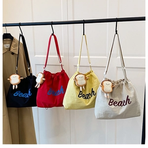 Detail of canvas drawstring tote bags in four colors with Beach print and cute charms