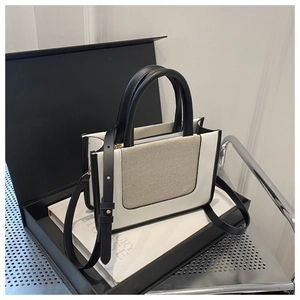 Detail of contrast stitch tote bag with leather straps and canvas panel on luxury display