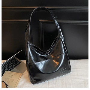 Detail shot of the large black glossy PU tote bag with a practical front pocket design