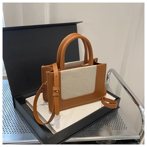 Detail of caramel brown and off-white canvas patchwork bag with golden zipper and handles