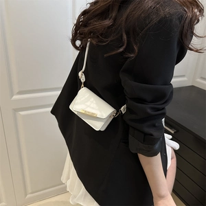 Mini sac à bandoulière crème avec barre dorée et foulard floral porté sur blazer noir