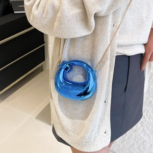 Metallic blue acrylic shell crossbody bag with a slim gold chain and mirror finish
