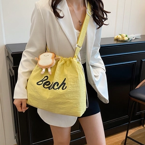 Minimalist bright yellow drawstring tote bag with Beach print and toast plush charm