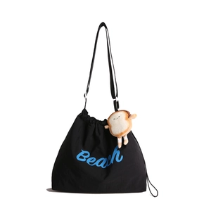Minimalist black canvas drawstring tote bag with blue Beach text and plush toast charm