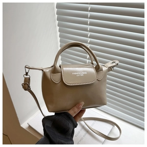 Detail of beige faux leather handbag with top handles and adjustable shoulder strap