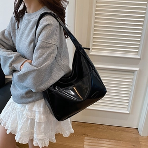 Grande borsa tote nera in pelle verniciata lucida da donna indossata a tracolla