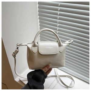 Detailed macro view of off-white faux leather mini handbag with text on front flap