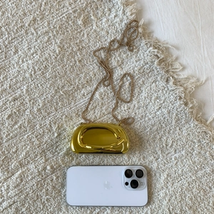 Macro view of gold mirror finish round evening clutch bag with delicate ball chain strap
