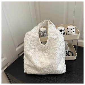 Close-up of white lace tote bag with delicate daisy embroidery and mesh texture