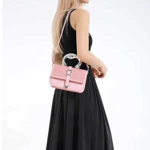 Pink crossbody bag with herringbone weave flap and silver metallic handle on a model