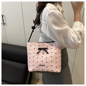 Detail of pink shoulder bag featuring floral texture, black bows and silver heart charm