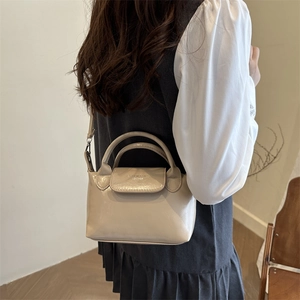 Fashionable off-white mini crossbody dumpling bag with smooth leather finish and top handles