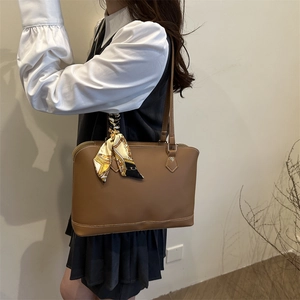 Brown leather tote bag for women with decorative scarf shown on a female model