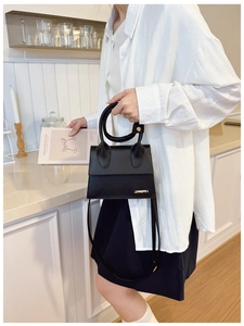 Détail du sac noir mat en cuir PU avec logo en métal doré et poignée ronde