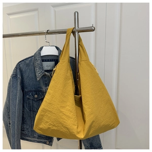Detailed texture of yellow canvas tote bag hanging next to a denim jacket in a bright room