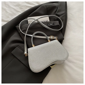 Silver glitter mini bag with curved bottom on dark suit jacket with fashion magazine