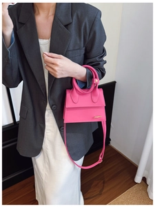 Détail du mini sac à main rose fuchsia en cuir avec anse arquée et perle dorée