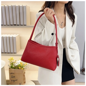 Detailed view of red woven leather shoulder bag texture on white blazer background