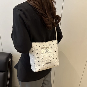 White bucket bag with black bow embroidery and heart pendant shown on model