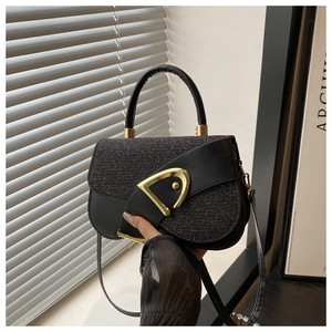 Detail of black saddle bag with glitter flap and iconic gold D-buckle on a prop book