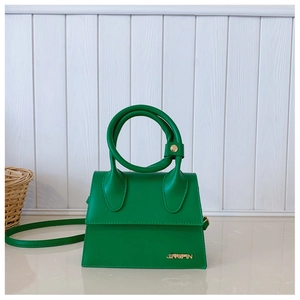 Détail d'un mini sac à main vert émeraude avec grande poignée ronde et logo doré élégant