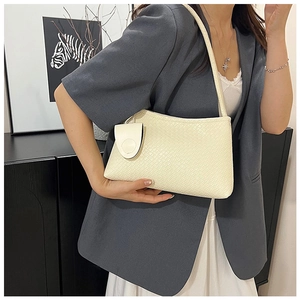 Detail of a creamy white woven shoulder bag with a small detachable coin purse accessory