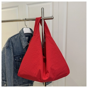 Detail view of large red nylon tote bag hanging on a rack showing textured fabric surface