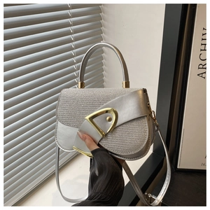 Detail of silver saddle bag with glitter texture and gold D buckle held by hand