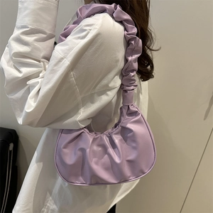 Purple pleated dumpling shoulder bag with cloud strap design shown on model shoulder