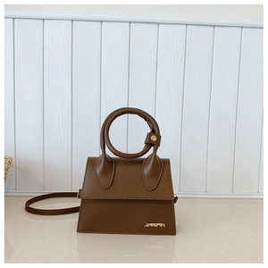 Détail macro d'un mini sac en cuir marron foncé avec poignée ronde et logo doré