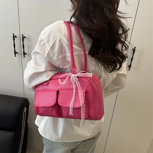 Sac à épaule rose avec deux poches avant et un nœud décoratif en dentelle blanche