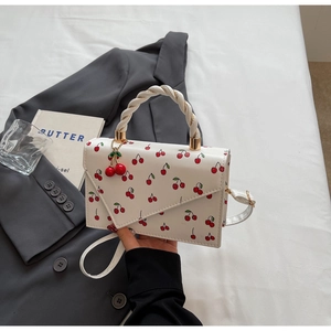 Vue détaillée du sac en cuir blanc avec imprimés cerises et un pendentif cerise 3D décoratif