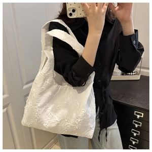 Detailed view of white floral lace embroidery on a large capacity summer tote bag