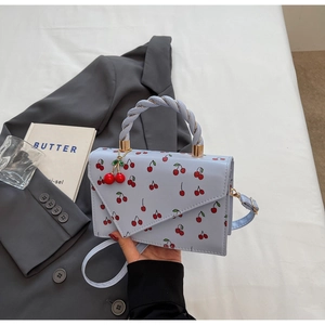 Détail du mini sac bleu clair avec motif cerises et poignée en corde torsadée