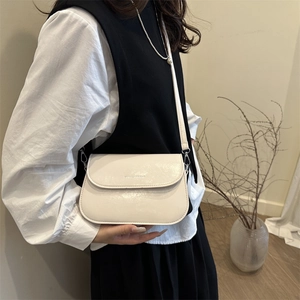 Sac à bandoulière minimaliste blanc crème avec rabat porté par un mannequin