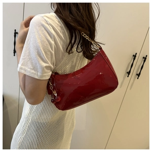 Sac bandoulière en cuir verni rouge avec breloque cerise et chaîne dorée sur mannequin
