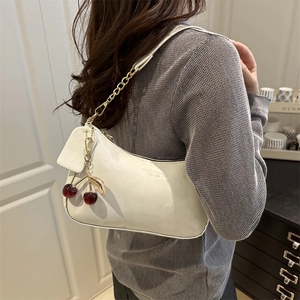 Glossy white patent leather underarm bag with gold chain strap and cherry charm detail