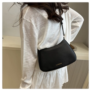 Close-up of black matte saddle bag with gold FASHION lettering and adjustable strap