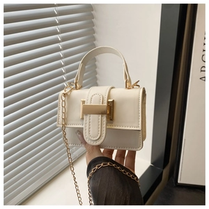 Detailed close-up of a mini white leather square bag with a gold buckle and chain strap