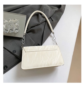 Detail of cream white crinkle texture baguette bag with silver metal chain link and strap