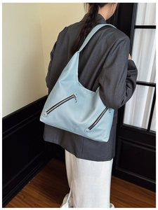 Detail of light blue hobo bag showing pebbled leather texture and dual zipper design