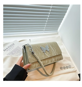 Close-up of creamy white quilted crossbody bag with elegant silver butterfly buckle